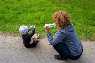 Woman and grandchild drinking from plastic bottle