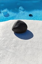 Rounded black lava stone at the edge of a pool