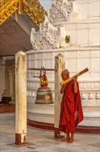 Monk ritually strikes a bell