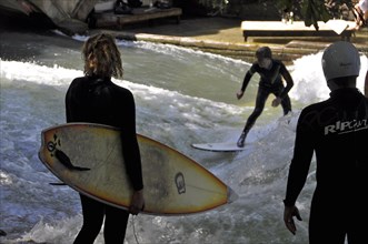 Sufers watch surfers riding the wave at the Eisbach