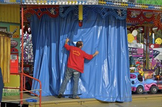 Showman draws curtain in front of his carousel