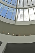 Visitor looking down in front of glass dome in Pinakothek der Moderne