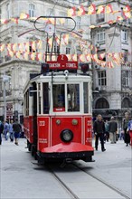 Historic tram Nostaljik Tramvay riding through shopping street Istiklal Caddesi