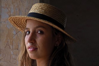 Young woman with straw hat and nose piercing