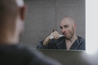 Man brushing his teeth in front of the bathroom mirror