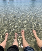 Two pairs of feet in the water
