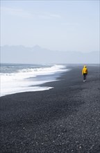 Woman walking on a black sand beach