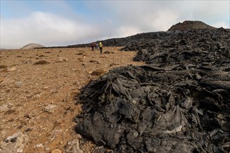 Tourists walk along cooled lava flows