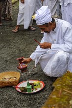 Hindu priest with basket and plate prepares offerings