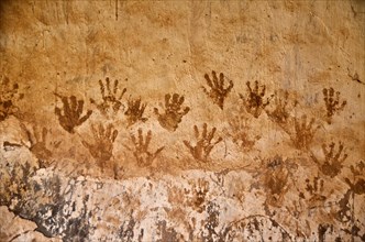 Handprints with henna on clay house wall