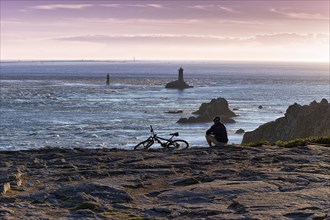 Cyclist sitting on rocky coast