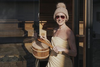 Woman with infusion tub in front of the sauna