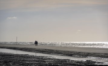 Walkers on the beach at low tide with tide pools
