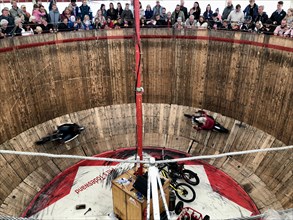 Spectators look down on motorcyclists on a steep wooden wall