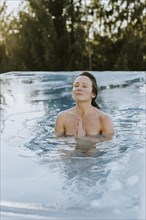 Woman folds her hands while ice bathing in the pool