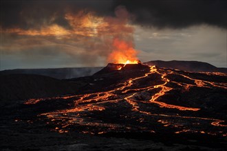Lava spurting out of crater and reddish illuminated smoke cloud