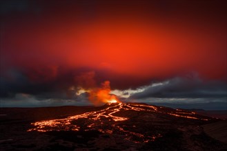 Lava spurting out of crater and reddish reflection on cloud