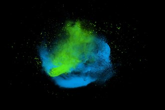 Freeze motion of blue and green powder paint exploding isolated on black