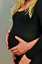 Man holds baby belly of pregnant woman dressed in black