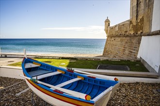 The wooden traditional boat and Saint James Fortress on the beach of Sesimbra