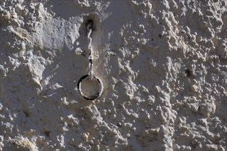 White wall with metal ring on chain