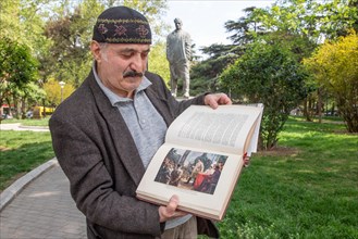 A man shows a book with pictures of Stalin