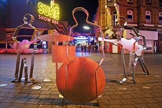 Beatles metal figures on Beatles Square at night