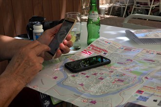 Tourist at table with mobile phone and city map