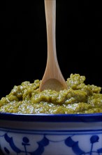 Green Thai curry paste in bowl with wooden spoon