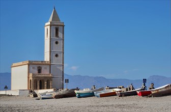 Church tower with boats on the beach of Salinas