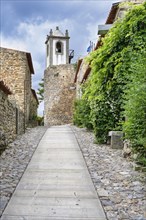 Narrow street and old stone tower