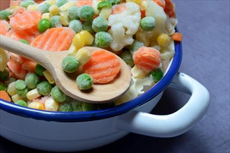 Frozen vegetables in bowl with cooking spoon