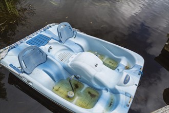 Blue Pelican pedal boat filled with rainwater in summer
