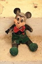 Demolished rag doll of a Mickey Mouse leaning against the wall