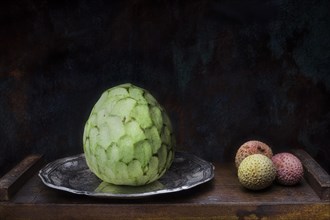 Still life with lychees and cherimoya fruit on silver plate