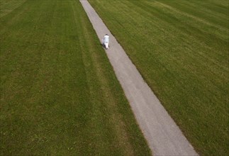 Frail woman walking with a Rolator along a narrow path