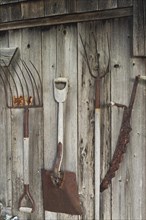 Antique hand tools displayed on exterior wall of old rustic wood plank cabin