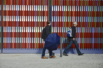 Two men walking in front of the colourful striped facade of the Museum Brandhorst