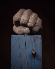 Still life with concrete fist Pendulum on wooden block