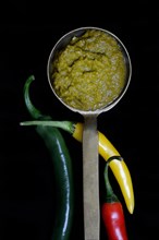 Thai green curry paste in ladle and chillies