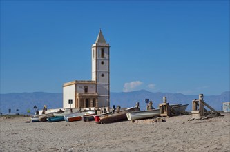 Church tower with boats on the beach of Salinas