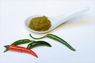 Green Thai curry paste in ceramic spoon and chillies