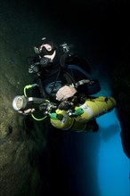 Diver dives into entrance of underwater cave with special equipment Diving equipment for cave divers