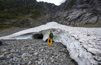 Hikers at the entrance of an ice cave of a glacier