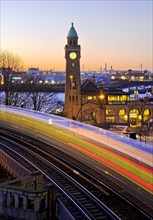 Atmospheric light trails of moving elevated railway and clock tower at sunrise