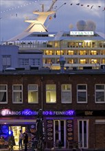 Fish market shops and cruise ship Artania at Hamburg Cruise Center Altona in the evening