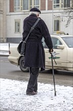 Senior citizen with walking stick in winter road conditions