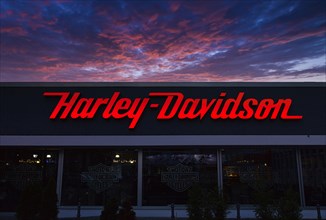 Illuminated Harley Davidson advertising sign at dusk