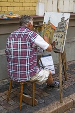 Painter in front of the ensemble of houses The Three Brothers
