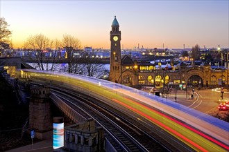 Atmospheric light trails of moving elevated railway and clock tower at sunrise